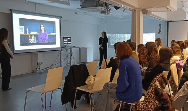 A classroom with students watching a screen where a videoconference is taking place