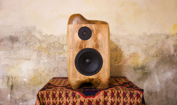 Wooden speaker placed on a table covered with a plaid blanket